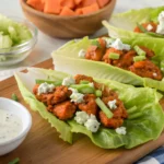 Buffalo Chicken Lettuce Wraps with spicy buffalo chicken, blue cheese crumbles, and green onions served with a side of ranch dressing.